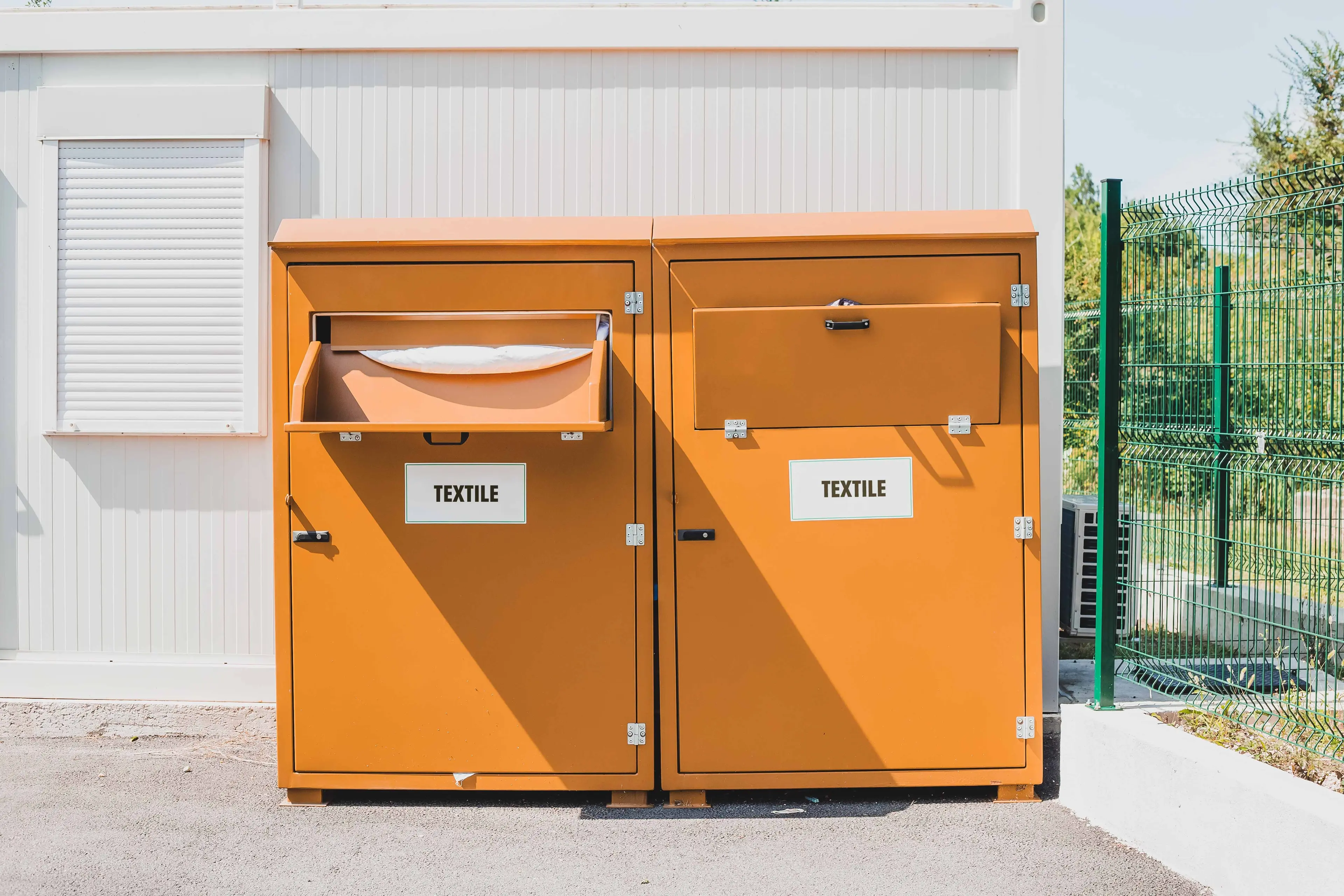 Two bright orange textiles recycling bins sitting adjacent to one another.