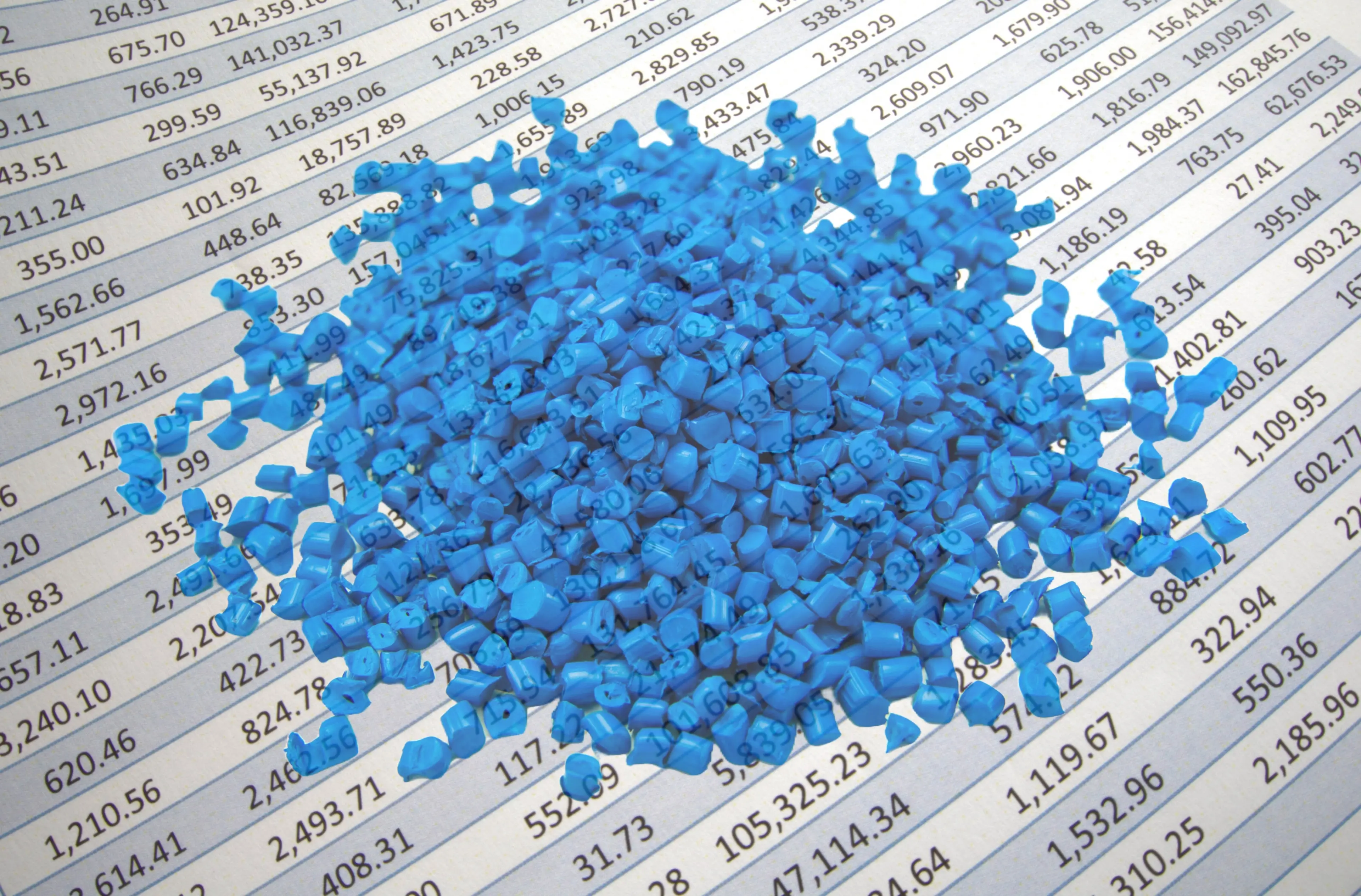 Blue plastic pellets laid on spreadsheet background